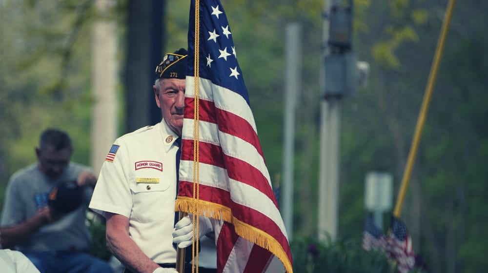 a veteran holding the American flag | Wounded Warrior Project Stealing Money From Vets | featured | warrior project