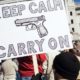 Protester holds keep calm carry on sign | Virginia Governor Bans Guns From State Capitol Ahead of Pro-Gun Rally | Featured