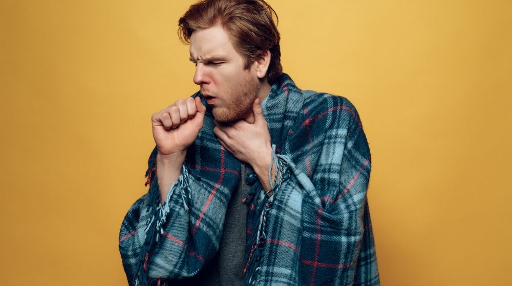 coughing and sick man | Young Sick Guy Wrapped in Checkered Plaid Coughing | Featured