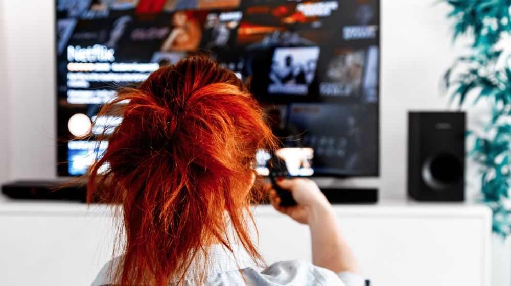 Woman with red hair watching Netflix | Netflix and Disney+ Could Benefit from Coronavirus | Featured
