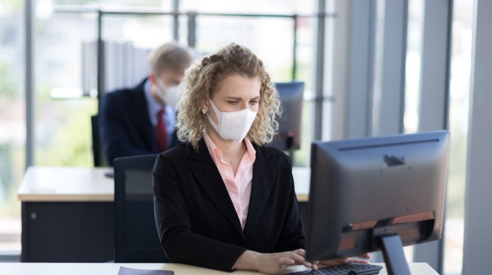 Lady in the office with face mask | JPMorgan Chase Asks Employees to Work From Home to Test a Coronavirus Contingency Plan | Featured