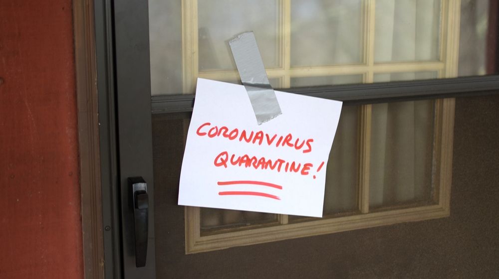 Coronavirus Quarantine written on a piece of paper | Michigan Governor Gretchen Whitmer’s Stay-at-Home Order Now Bans Traveling to Another Home | Featured
