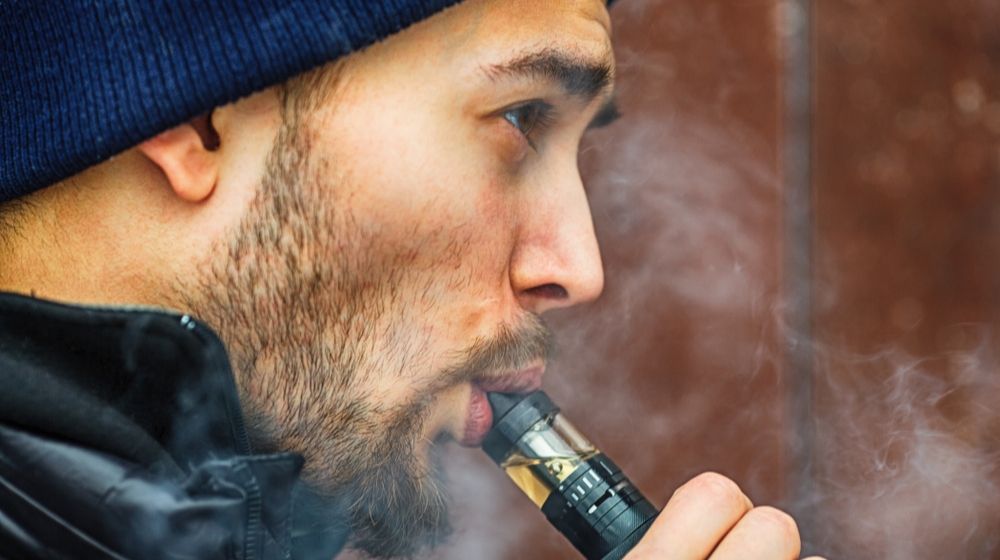 Man using a vape | House Oversight Committee Urges FDA to “Clear the Market” of E-Cigarettes Following Coronavirus Concerns | Featured