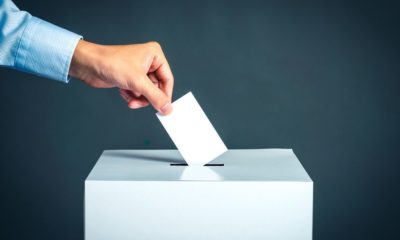 man putting his vote in a box | Nineteen People Involved in Election Day Activities in Wisconsin Test Positive for the Coronavirus | Featured