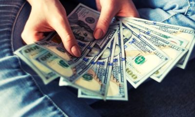 girl holding dollar bills | As Americans Begin Receiving Checks, What’s Next for Coronavirus Stimulus | Featured