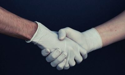 shaking hands with gloves | U.S. Records Lowest Number of COVID-19 Deaths in Two Weeks | Featured