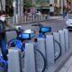 A Woman with Personal Protective Equipment Parking a Citi Bike | Robert Kaplan Says U.S. Economy’s Recovery May Depend on Success in Limiting Spread of COVID-19 | Featured