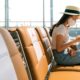 Female Tourist wearing Mask using Mobile Phone | Travelers Must Assess Risk When Flying to Avoid COVID-19 | Featured