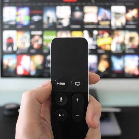 Hand Holding a TV Remote while Watching Shows on a Streaming Service on Television | Interactive Site Shows Physical Effects of Binge-Watching | Featured