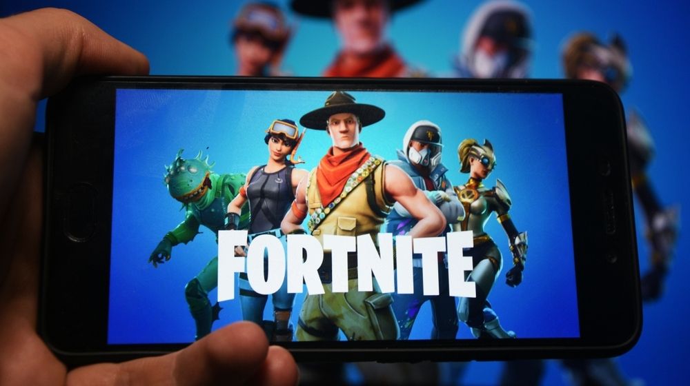 Hand Holding Phone with Fortnite Logo Displayed in it | “Fortnite” Removes Police Cars in New Update | Featured
