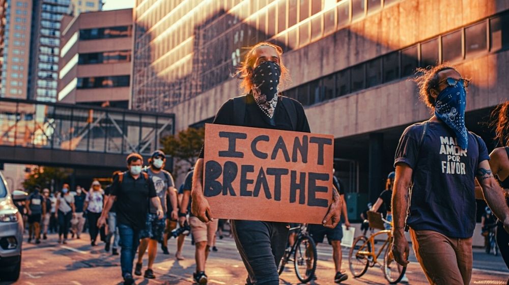 Man holding a sign I can't breathe | Minneapolis City Council Weighs “Dismantling” Police Department | Featured
