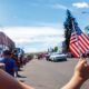 Girl Holding USA Flag at 4th of July Parade Festival Celebration | July 4 is a Time to Celebrate, Not Denigrate, the U.S.A. and its Birth | Commentary | Featured