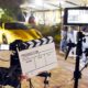 Operator Holding Clapperboard During the Production of Short Film Outdoor in the Night with Sportive Yellow Car | Movie Studios Must Undergo a Lot of COVID-19 Tests to Stay Secure and Open | Featured