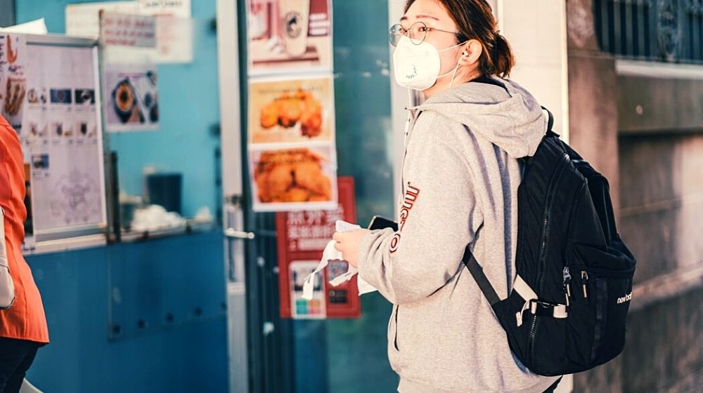 woman in hoodie wearing a mask | It’s Still Too Early to Tell If You Can Get the Coronavirus Twice | FEatured