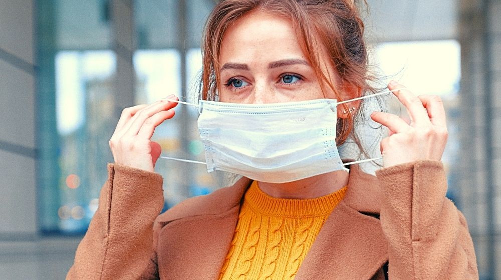 woman wearing a surgical mask | Johns Hopkins Senior Scholar and Coronavirus Expert Says Face Coverings Are a Vital Defense | Featured