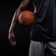 Cropped Image of Afro American Basketball Player Holding a Ball Against Dark Background | Jonathan Isaac Stands During National Anthem and Doesn’t Wear BLM Shirt; Jersey Sales Surge | Featured