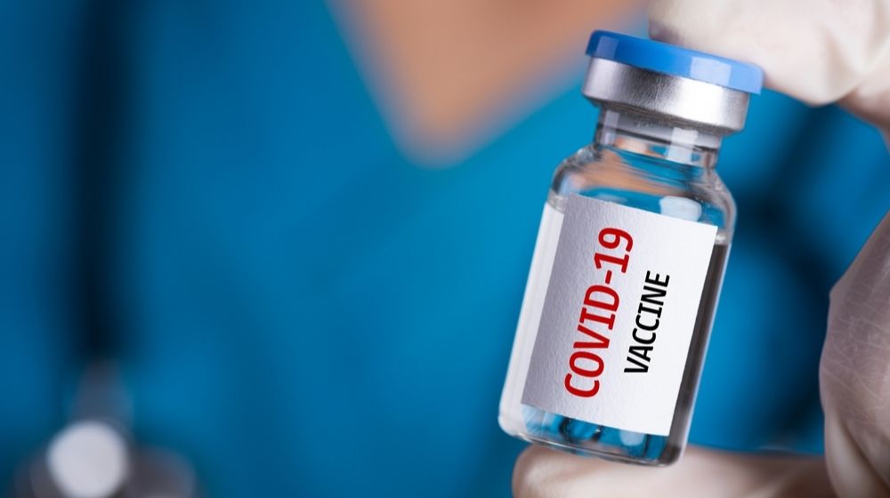 Doctor with a Stethoscope on Shoulder Holding a COVID-19 Vaccine | Russia Announces COVID-19 Vaccine, But Western Docs Doubt Safety Standards | Featured