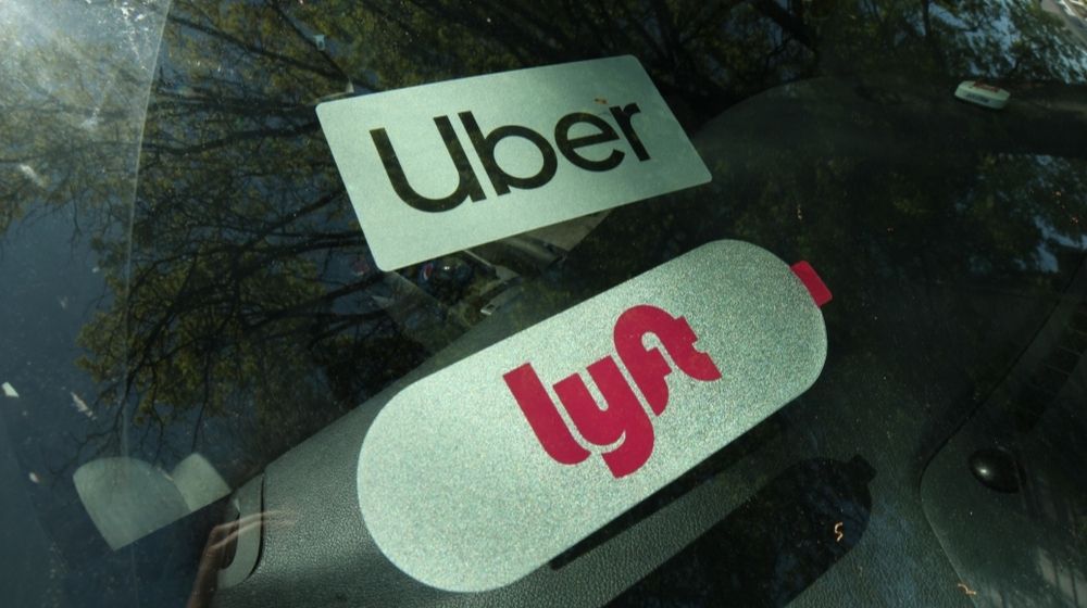 Lyft and Uber Sign on a Car | Judge Says Uber and Lyft Must Classify California Drivers as Employees | Featured