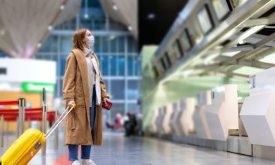 Woman with Luggage Stands at Almost Empty Check-in Counters | U.S. Officials Looking to Shorten Quarantine Time for New York-London Travels