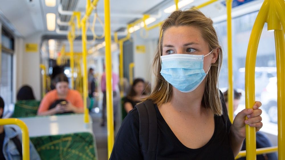 Young Woman Wearing a Face Mask Riding Public Transport | Recent Study Finds That Younger Generations Are More Likely to Lose Their Health Coverage Due to Pandemic | Featured