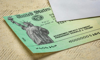 A stimulus check sample under a white letter envelope-Democrats Seek to Restart Stimulus Talks-ss-featured