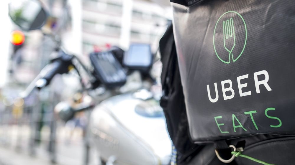 An Uber Eats Motorbike Parked on the Side of the Road | Uber Eats Accused of Discrimination for Waiving Delivery Fees for Some Black-Owned Restaurants | Featured