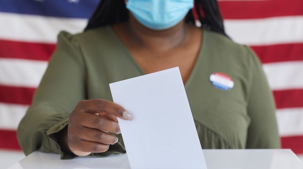 African-American Woman Wearing Mask Putting Vote Bulletin in Ballot Box | Blue Whimper: MSM’s Democratic Landslide Was Wishful Thinking| Featured