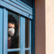 Man with mask in quarantine, looking outide the window-Governors Reinstate Severe Lockdowns as COVID-19 Cases Increase-ss-featured