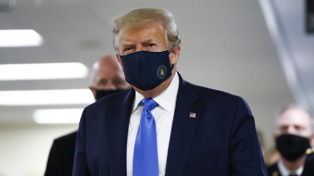 President Donald Trump wears a mask as he walks down the hallway during his visit to Walter Reed National Military Medical Center in Bethesda-Coronavirus Vaccines Delivery-ss-featured