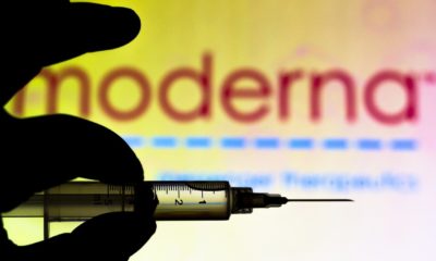 the-medical-syringe-coronavirus-vaccine-is-seen-with-Moderna-Therapeutics-company-logo-displayed-on-a-screen-in-the-background-Coronavirus-Vaccine-News-ss-featured