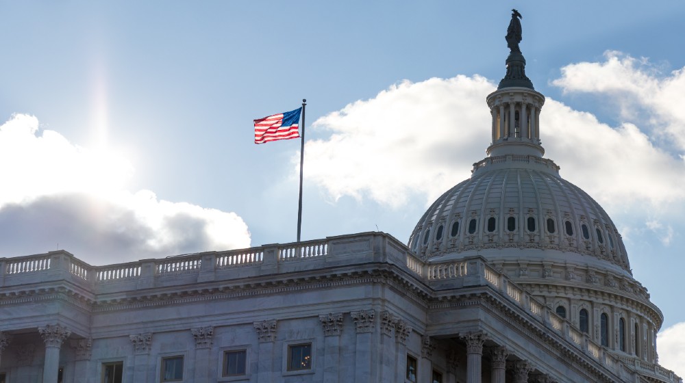 American flag waving atop of United States Capitol Building as the sun shines brightTrump’s Defense Bill Veto-ss-featured