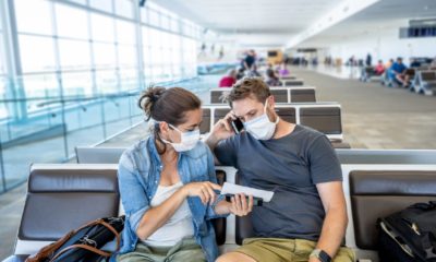 COVID-19 worldwide borders closures. Couple with face mask stuck in airport terminal after being denied entry to other countries-Coronavirus State Restrictions-ss-featured