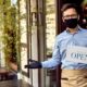 Happy waiter with protective face mask holding open sign while standing at cafe doorway-new ppp loans-ss-featured