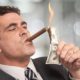 Rich businessman lighting cigar with $100 dollar bill-Trickle Down Economics Doesn't Work-ss-featured