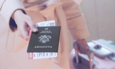 Woman with suitcase holding passport and boarding pass-2021 Travel Could Include Vaccine Passports-ss-featured