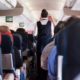 Flight attendant walking down the aisle of a passenger plane-Flight Attendants Union Wants Trump Supporters To Be Banned From Flights-ss-featured