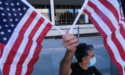 An immigration activist holding US flags- Lawmakers Warn Biden on Immigration Order Will Cause Crisis Overnight-ss-Featured