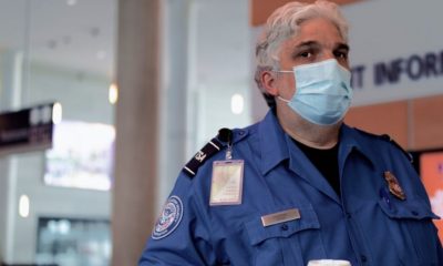 TSA agent wearing a facemask-TSA Will Require Travelers to Wear Facemask in Airports and Planes-ss-Featured