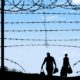 A man and woman are seen in silhouette after breaching a border fence on the southern border of the USA-US Southern Border-ss-featured