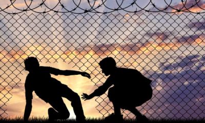 Concept of the refugees. Silhouette of refugees crossed the border illegally through the hole in the fence-Biden’s Border Policies-SS-Featured