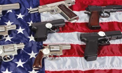 National firearms act - Pistols and revolver assorted firearms for sale on USA America flag at gun show-US Gun Sales-ss-featured