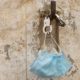 medical mask and handcuffs hang on a stone wall on a hook-Fraud-SS-Featured