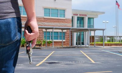 A young man with a pistol gun is standing in front of a high school preparing to commit a crime-School Shooter | School Shooter Dead, Officer Wounded in Knoxville Incident | Featured