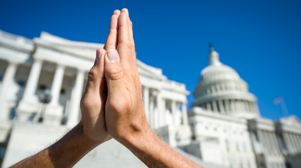 Hands held together in prayer in front on Capitol Building in Washington DC-Christian Minister-ss-featured
