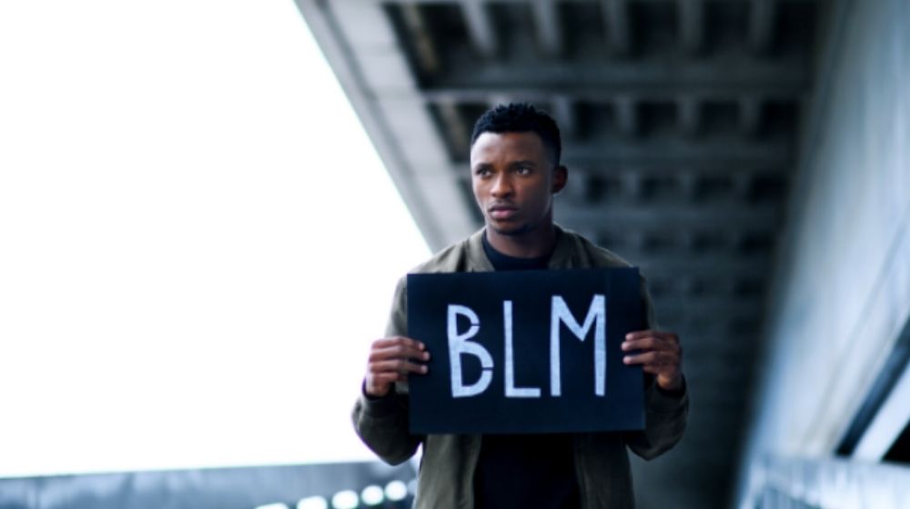 Man holding BLM sign-BLM Admits Communities Are Far Worse Off Under Biden Than Trump-ss-Featured
