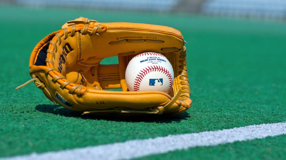 official Major League Baseball ball and glove on the green field-woke companies-ss-featured