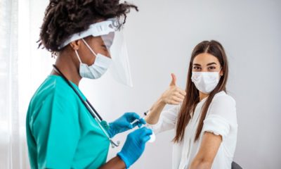 Successful Coronavirus Vaccination. Happy Vaccinated Teen Girl Gesturing Thumbs Up After Covid-19 Vaccine Injection In Hospital | Biden announces new COVID vaccine goals, plan for teens | Featured