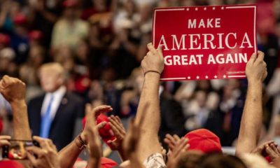 A fan holds up a Make America Great Again sign while President Donald J. Trump delivers a speech | Trump Alabama Rally Cancelled Due To Partisan Politics | featured