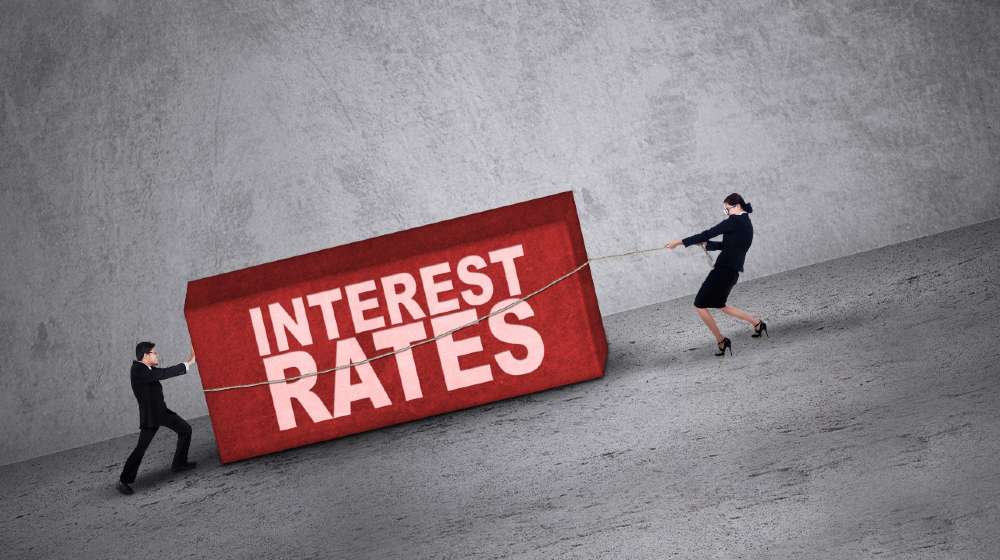 Business people trying to get a block with interest rates word on it | Economic Impacts Of Inflation And Rising Interest Rates | featured