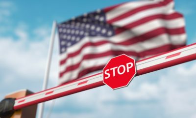 Closed boom barrier with stop sign against the American flag. Restricted entry or certain ban in the USA | VP Harris Tells Guatemalans: “Do Not Come” | featured
